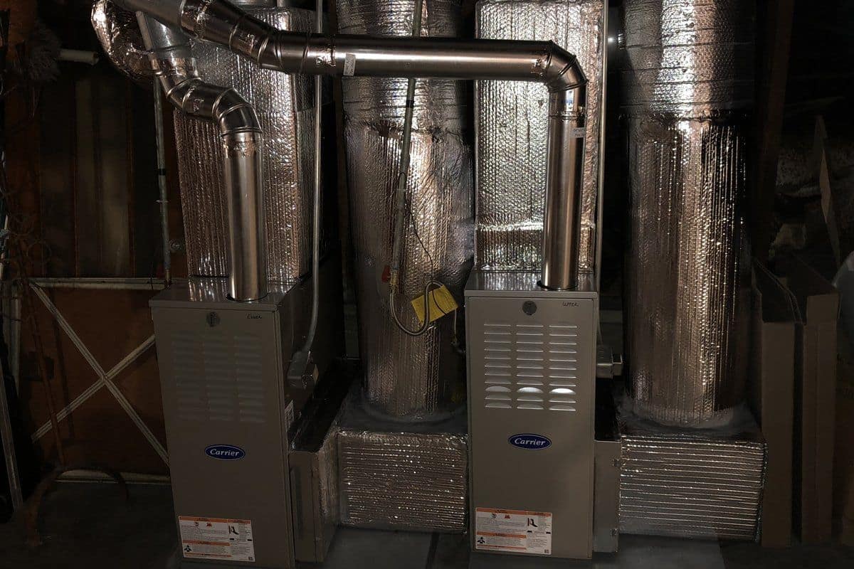 New sheet metal plenums and insulated duct trunks installed above two residential furnaces